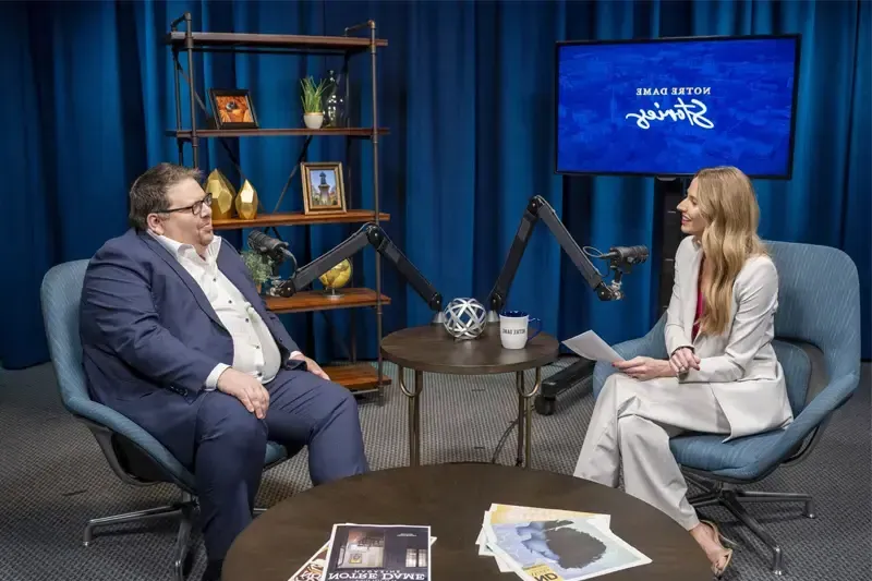 Jenna Liberto sits with Jeff Rhoads in front of podcast equipment